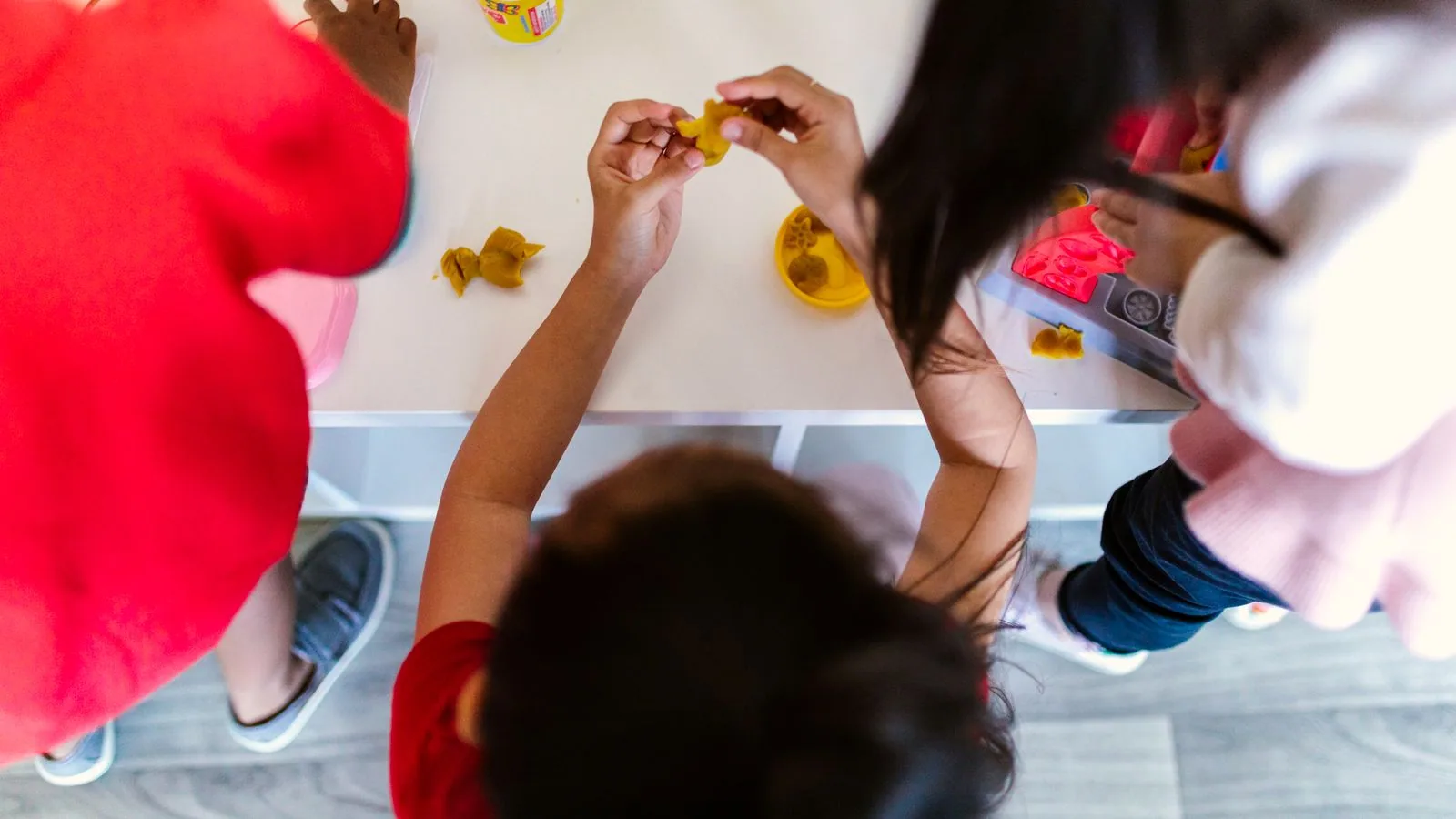 Photographie : des pâtes à modeler colorées et des mains d’enfant